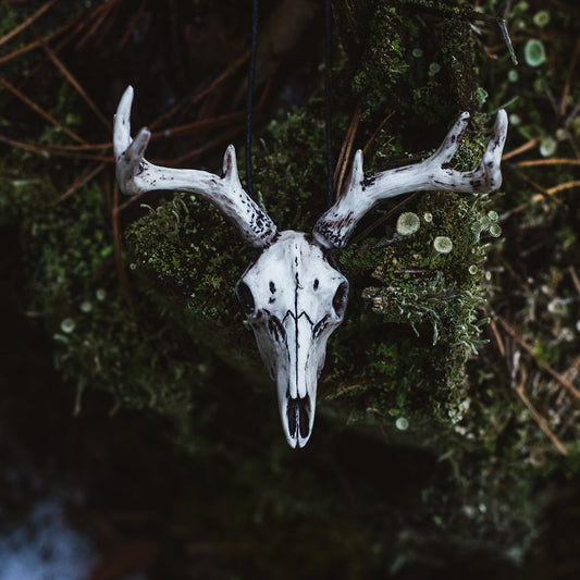 Handmade deer skull pendant with horns on moss background